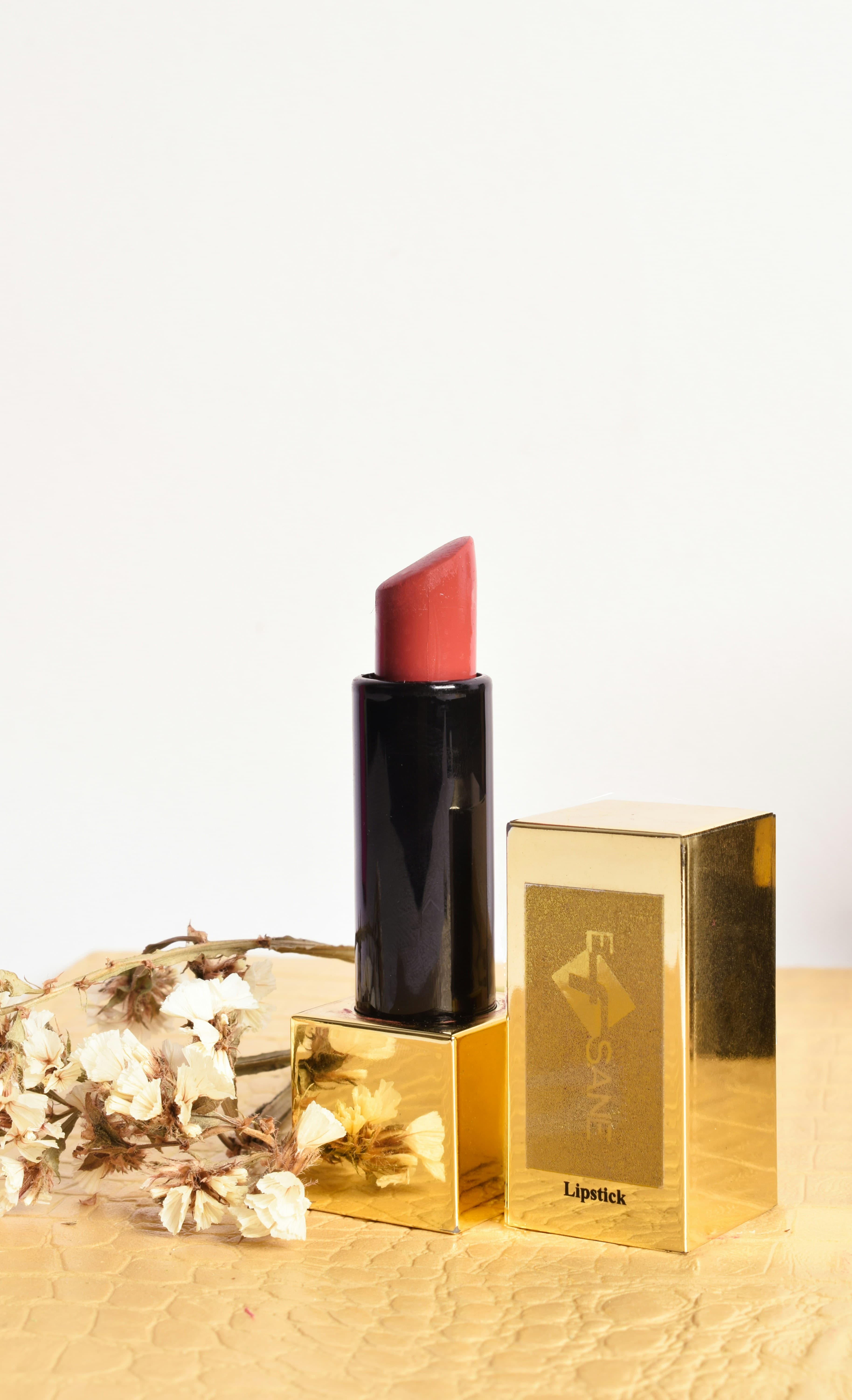 Lakme lipstick in deep red shade with gold packaging on pink surface